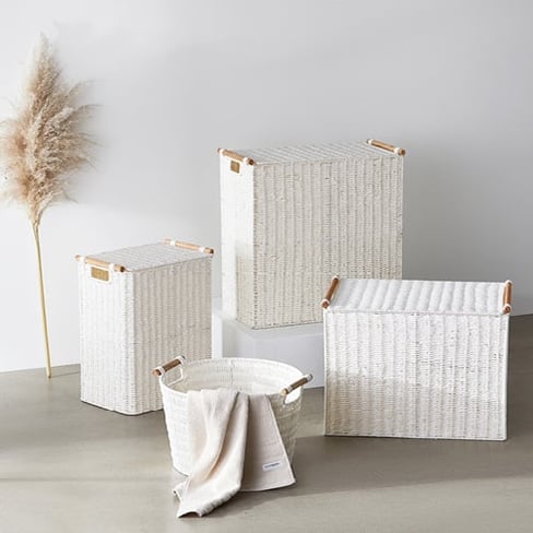Various white laundry baskets displayed behind a small round basket with a white towel inside