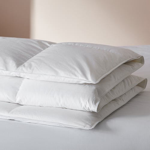 Feather and down quilt folded and placed on top of a bed.