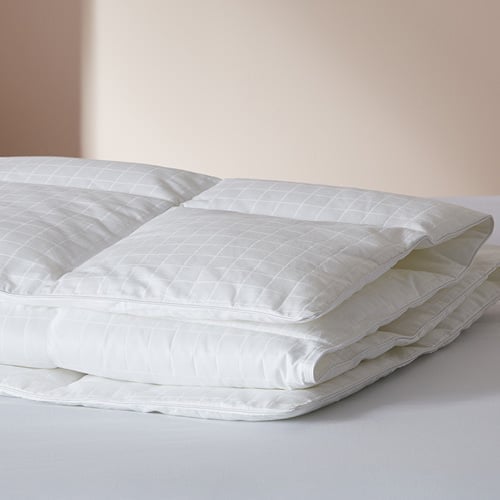 Memory fibre (polyester) quilt folded and placed on top of a bed.