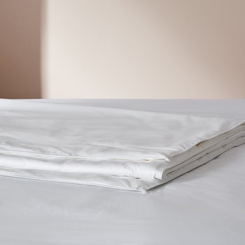 Silk quilt folded and placed on top of a bed.