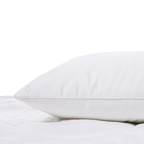 Bamboo pillow resting on top of a mattress with a protector. 