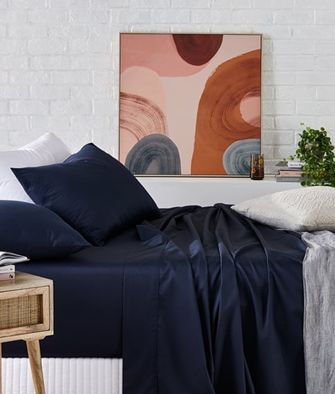 bed with navy cotton sheet and matching pillows