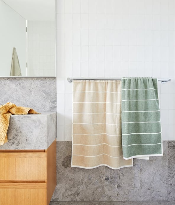 Bathroom setting with green and light brown towels placed on a towel rack