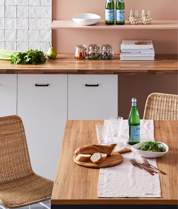 Kitchen scene with white linen table runner placed on a dining table with cutlery and food