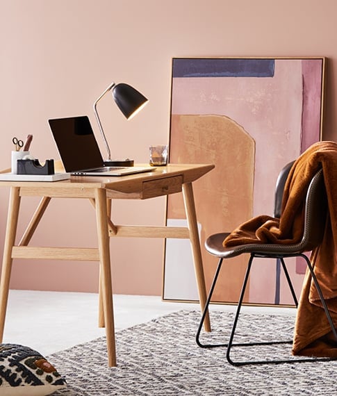 Study with desk and Orlando Tan Chair, and a rug underneath also styled with a warm-hued wall art piece leaning against the wall. 