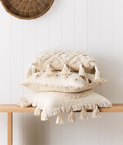 Stack of three neutral cushions with tassels, tufting and beautiful coastal details. 