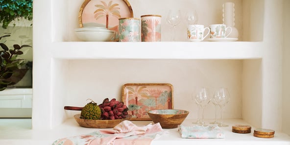 Karina Jambrak x Adairs servingware across two shelves including serving trays, bowl, tea towels, cannisters and more.