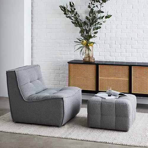Otis Lounge Chair in dark grey with matching footrest and behind is a Boden Black & Natural 3 Door Sideboard with vase on top. 