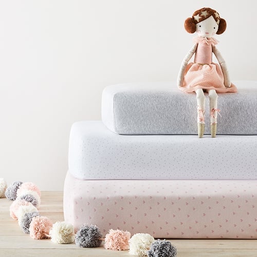 Stack of three mattresses – two singles with printed sheets and a cot mattress on top with grey marle sheet.