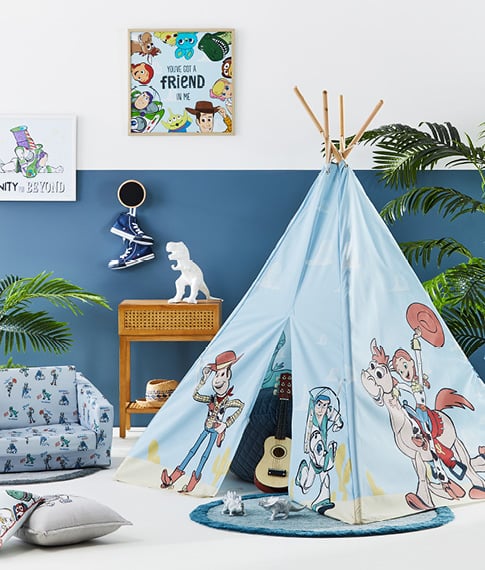 toy story themed kids play area with a kids teepee, foldable plush couch and light brown table, as well as a toy story canvas on the wall