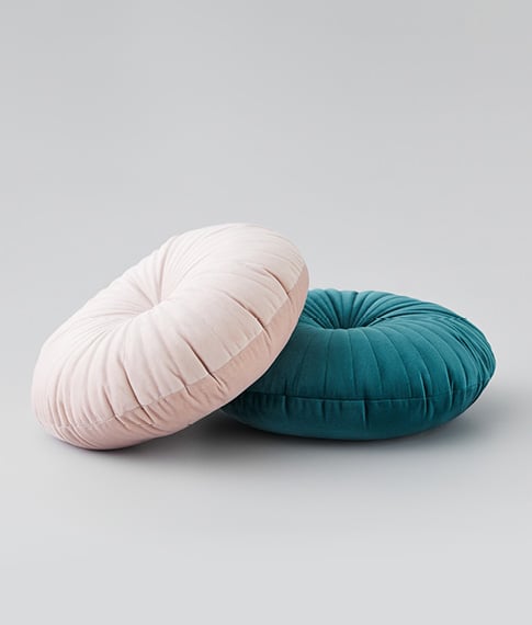 pink round pillow leaning against a dark green pillow