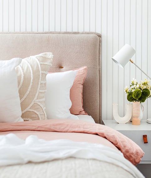 Close-up of bedlinen styled with neutral bedlinen and accessories in pink, white and neutral linen. 