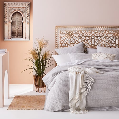 Bedroom displaying a bed with grey quilt cover and cushions, complimented with a white throw