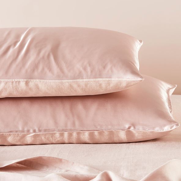 Two pink silk pillows stacked on top of each other.