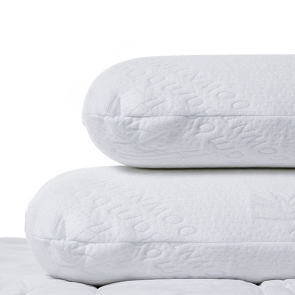 Two memory foam pillows stacked on top of each other sitting on a bed. 