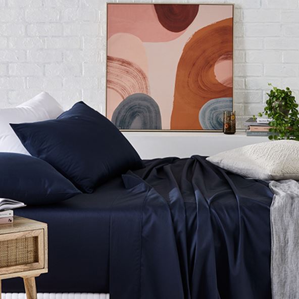 bed with navy cotton sheet and matching pillows