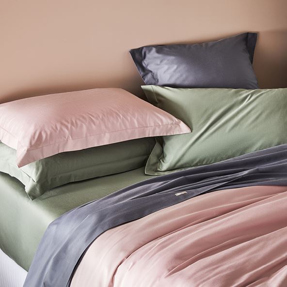Side-on view of bed styled with bamboo bedlinen including in pink, purple and green. 