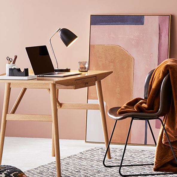 Study with desk and Orlando Tan Chair, and a rug underneath also styled with a warm-hued wall art piece leaning against the wall. 