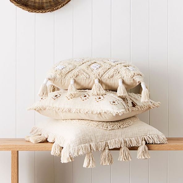 Stack of three neutral cushions with tassels, tufting and beautiful coastal details. 