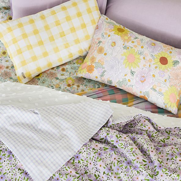 Bird’s eye view of a bed styled with multiple different pastel prints, checks and floral bedlinen.