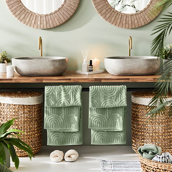 Double-vanity styled with matching rattan laundry baskets, textured towels, and marble bathroom accessories. 