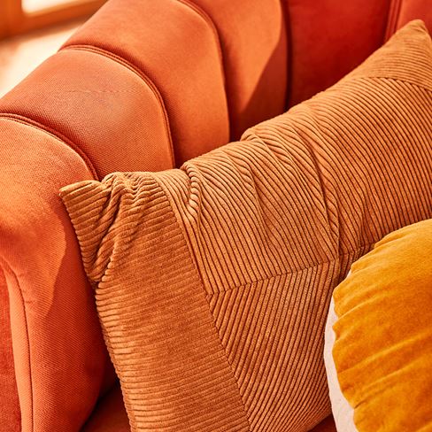 A close up shot of orange cushions on an orange chair, all slightly different shades and textures.