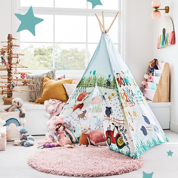 Kids playroom with bench seat in the background, a bookshelf and a tepee filled with plush toys in the foreground. 