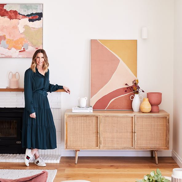 Stylist Kerrie-Ann Jones leaning against a fireplace next to the Anjuna Collection Sideboard styled with accessories. 