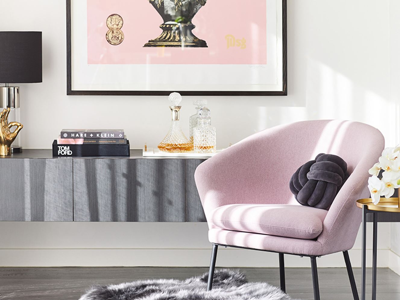 Bedroom corner styled with a pink armchair, and velvet navy blue knotted round cushion.